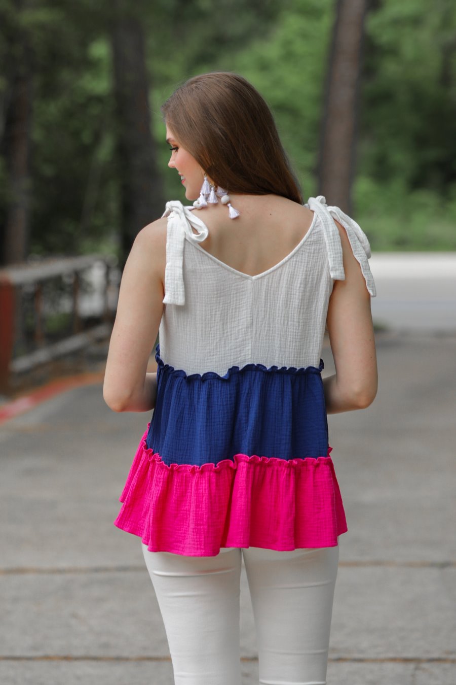 a pink tiered color block top with a V-neckline front and back, adjustable wide tie straps, a ruffled hem, and a relaxed, lightweight fit