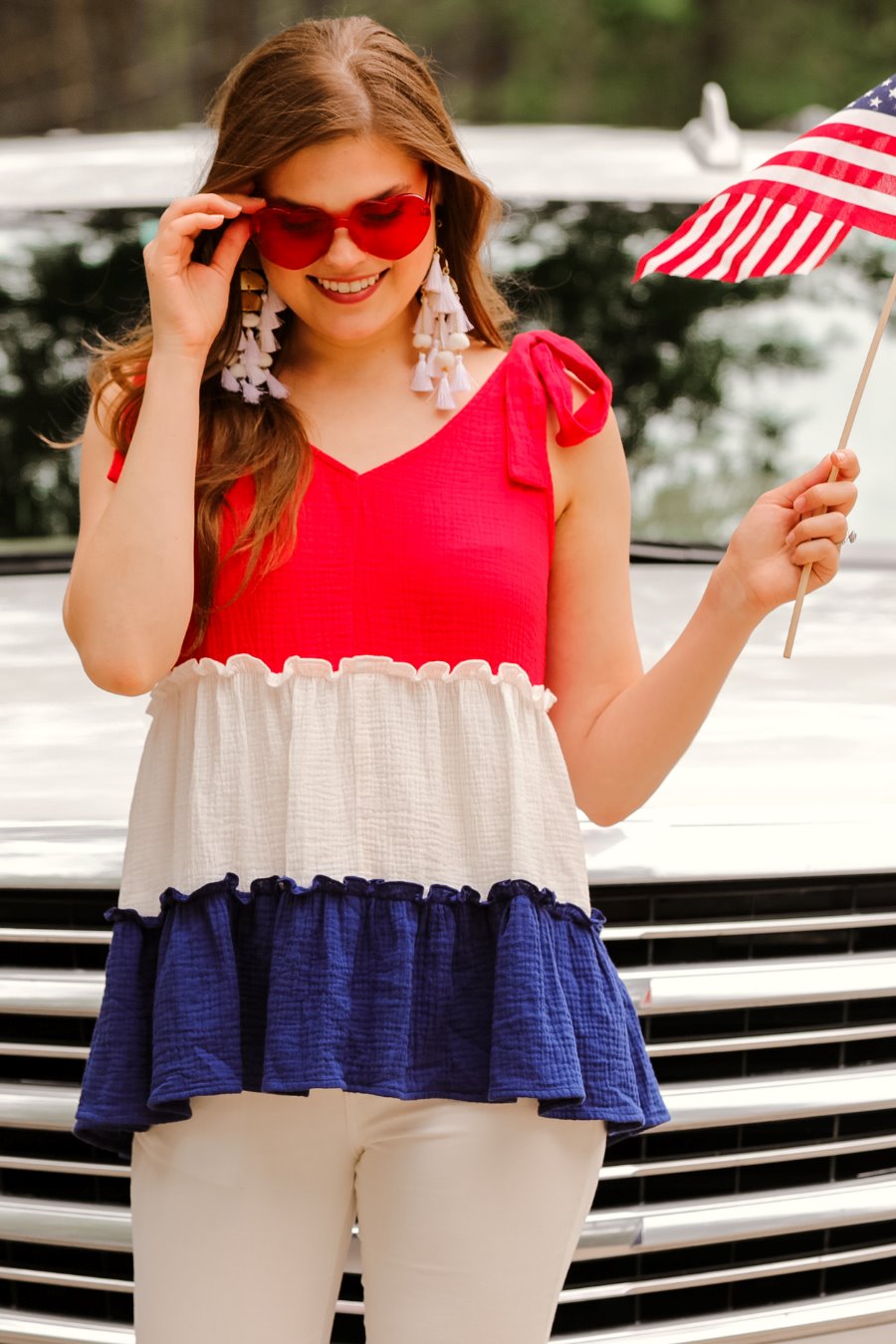 a red tiered color block top with a V-neckline front and back, adjustable wide tie straps, a ruffled hem, and a relaxed, lightweight fit