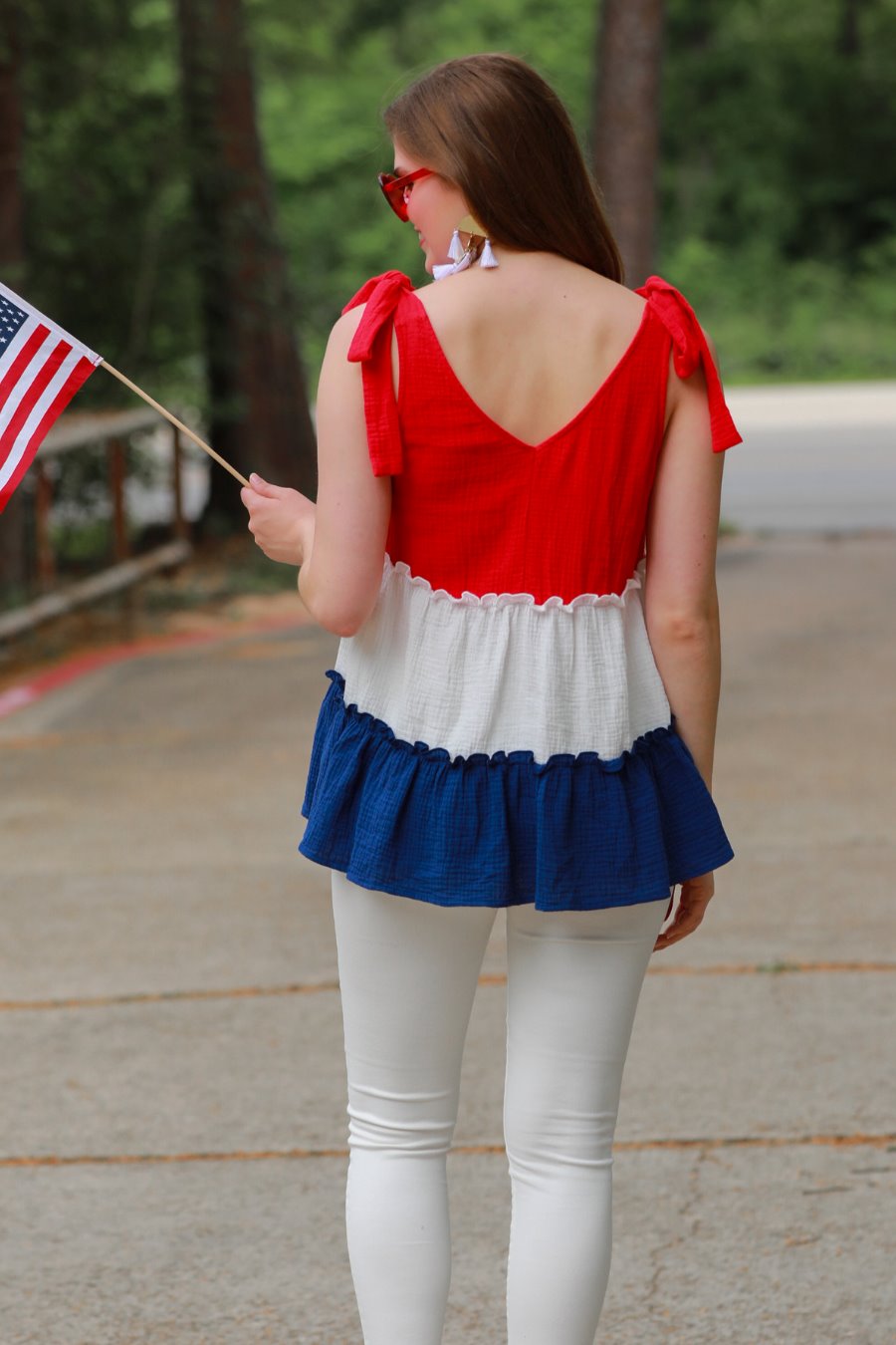 a red tiered color block top with a V-neckline front and back, adjustable wide tie straps, a ruffled hem, and a relaxed, lightweight fit