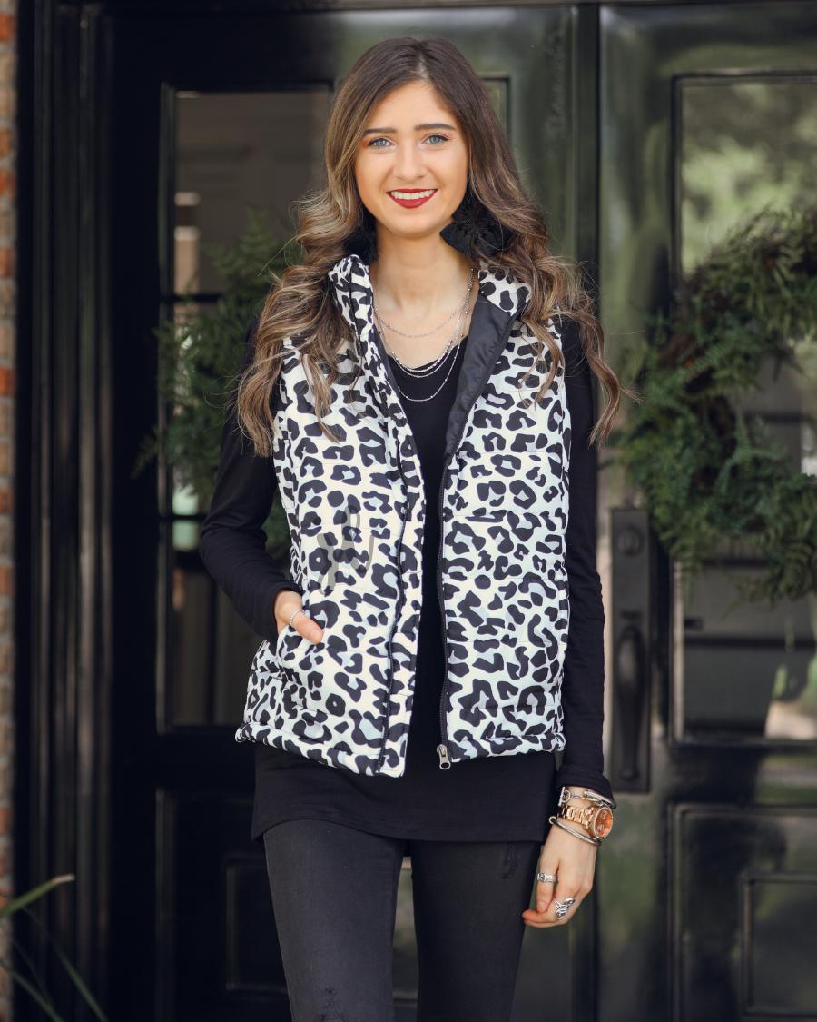 sleeveless puffer vest with a full front zipper closure, a collared neckline, and zippered hidden pockets on a fully lined quilted fabric in a black, grey, and white leopard print with black detail accents