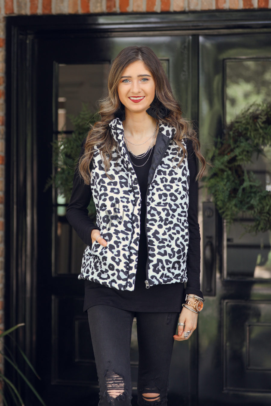 sleeveless puffer vest with a full front zipper closure, a collared neckline, and zippered hidden pockets on a fully lined quilted fabric in a black, grey, and white leopard print with black detail accents