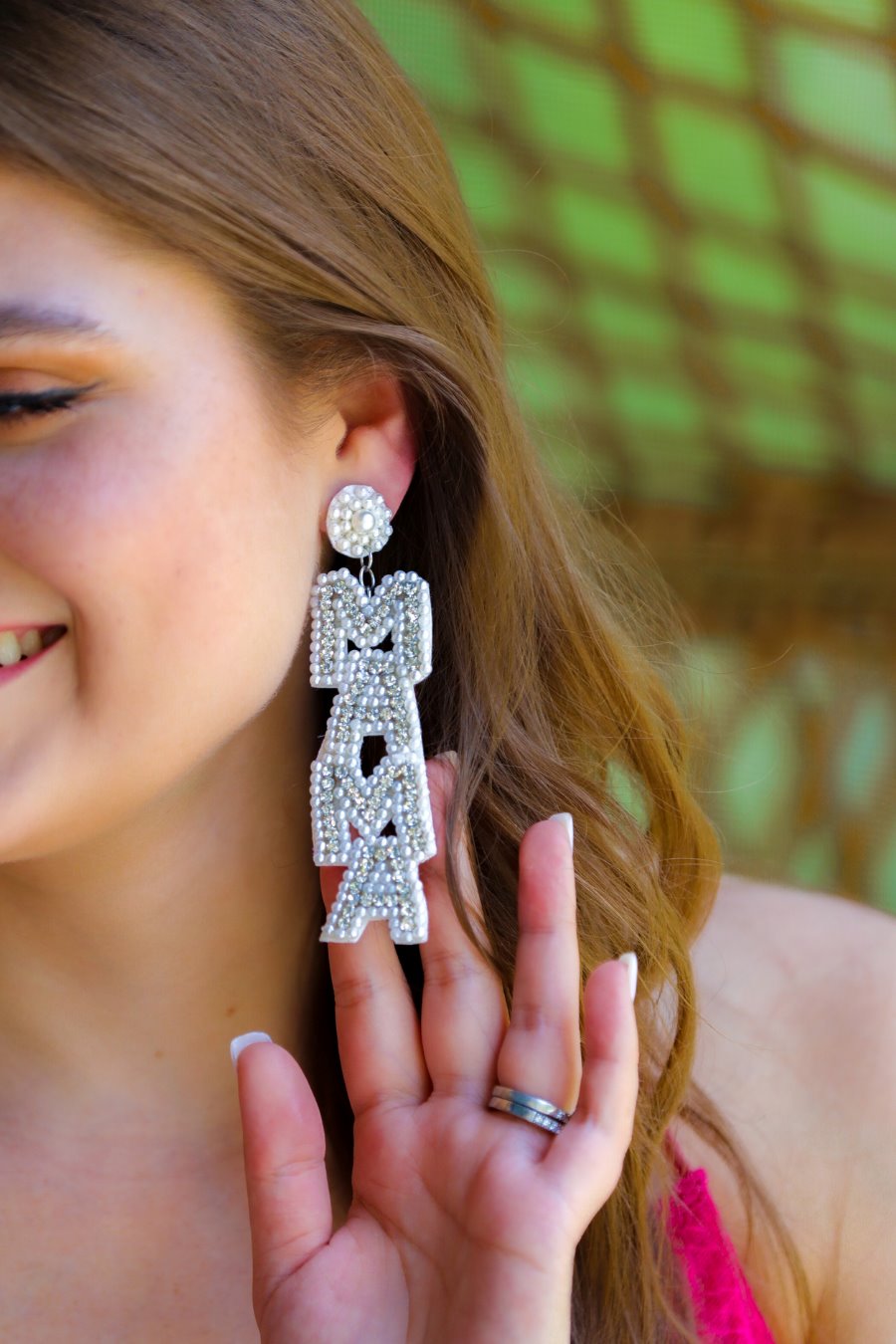 oversized dangle drop earrings with stacked 'MAMA' lettering in luminous white pearls and shimmering silver rhinestones, a pearl accented stud top, a comfort back earring with a plastic disc stopper in gold, and a white felt back