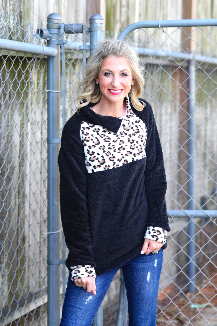 a long-sleeve pullover crafted from plush fleece with a striking ivory leopard accent across the bodice with coordinating leopard cuffs, silver side snap detailing along the shoulder, and a fold over collar