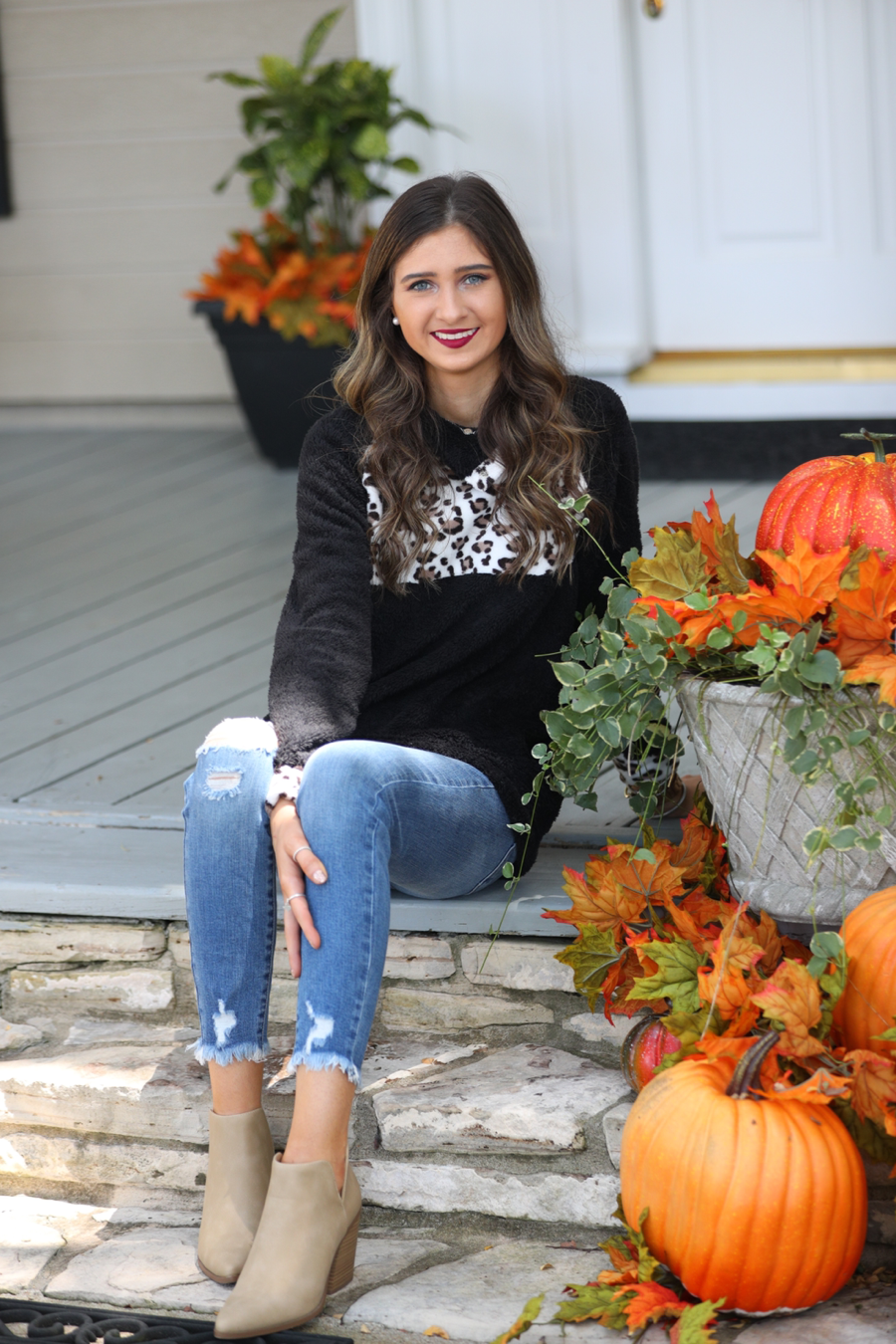 a long-sleeve pullover crafted from plush fleece with a striking ivory leopard accent across the bodice with coordinating leopard cuffs, silver side snap detailing along the shoulder, and a fold over collar