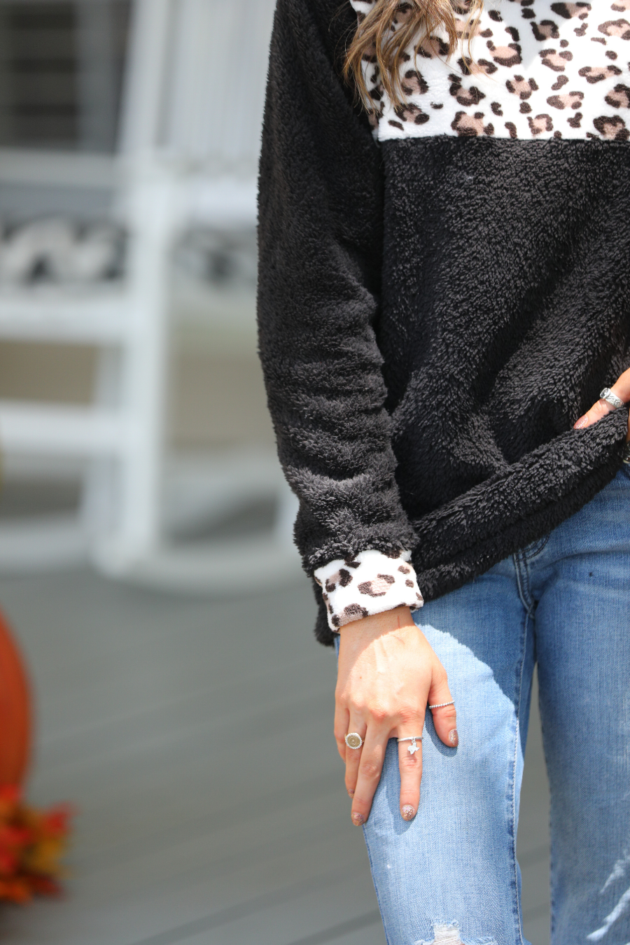 a long-sleeve pullover crafted from plush fleece with a striking ivory leopard accent across the bodice with coordinating leopard cuffs, silver side snap detailing along the shoulder, and a fold over collar