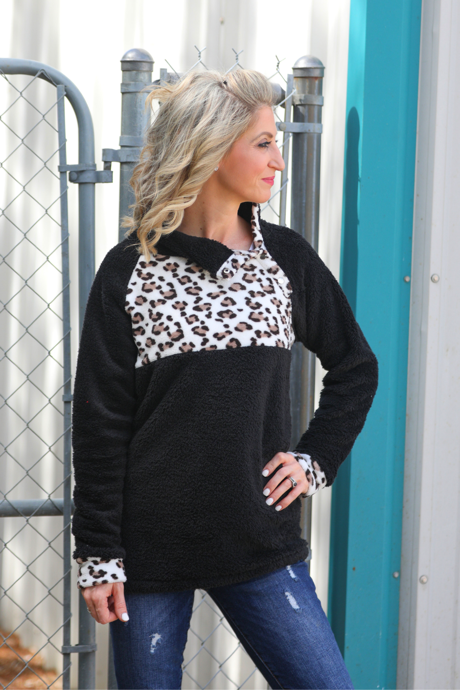 a long-sleeve pullover crafted from plush fleece with a striking ivory leopard accent across the bodice with coordinating leopard cuffs, silver side snap detailing along the shoulder, and a fold over collar