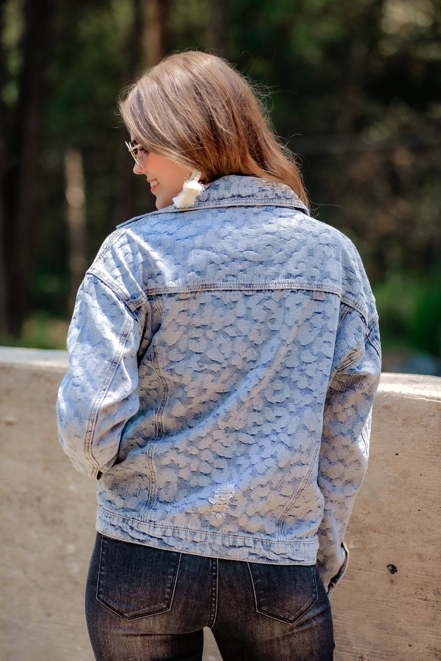 relaxed-fit jacket crafted from light wash denim with subtle distressing and faded leopard print accents, a button-down front, collared neckline, flap chest pockets, rollable long sleeves with buttoned cuffs, and a straight hemline
