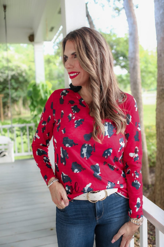 red long-sleeve top with a v-neck on a black & white leopard print pattern