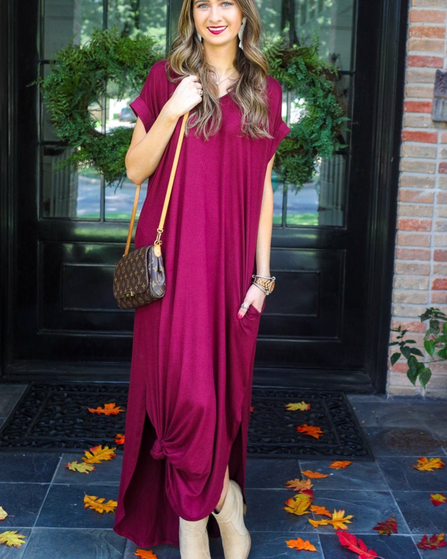 oversized short-sleeve t-shirt dress crafted from soft, stretchy material with a V-neckline, cuffed sleeves, side slits, and pockets on a solid burgundy fabric