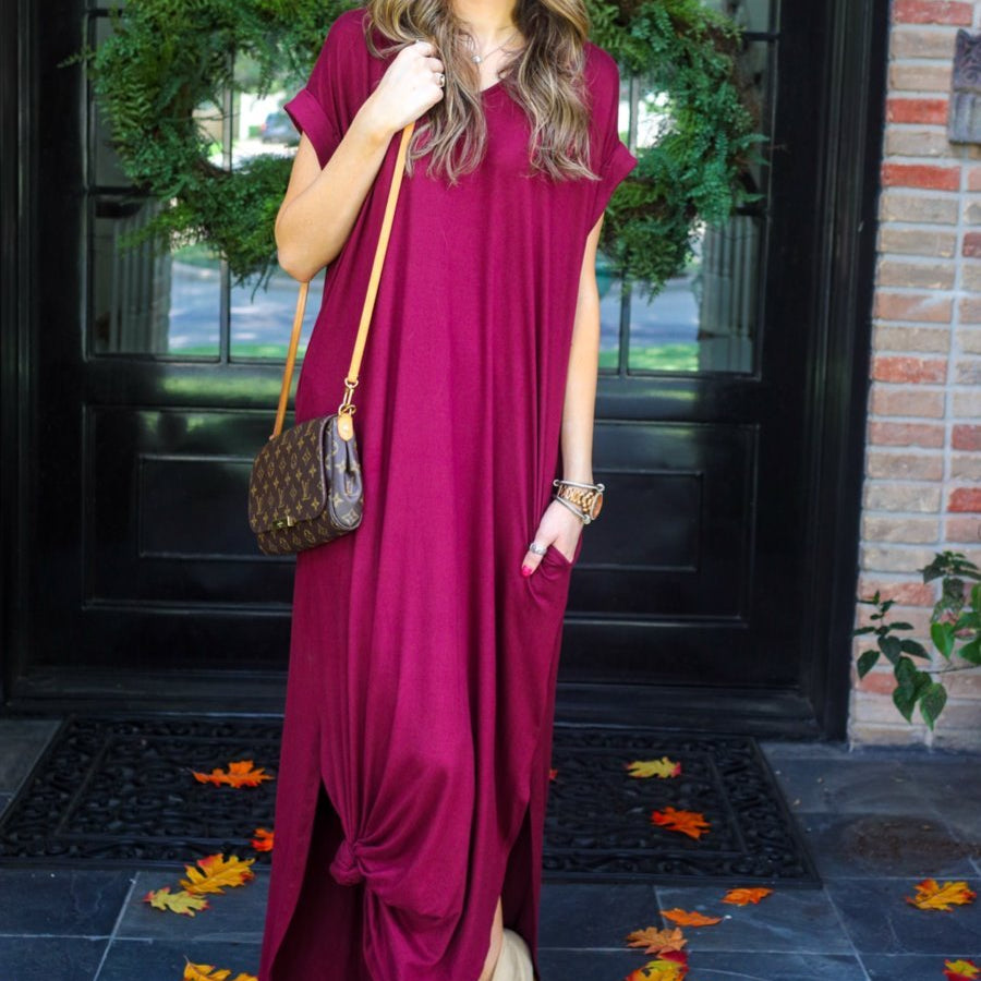 oversized short-sleeve t-shirt dress crafted from soft, stretchy material with a V-neckline, cuffed sleeves, side slits, and pockets on a solid burgundy fabric