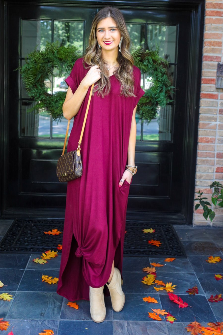 oversized short-sleeve t-shirt dress crafted from soft, stretchy material with a V-neckline, cuffed sleeves, side slits, and pockets on a solid burgundy fabric