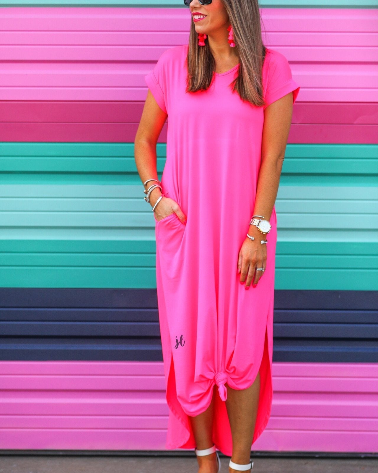 oversized short-sleeve t-shirt dress crafted from soft, stretchy material with a V-neckline, cuffed sleeves, side slits, and pockets on a solid hot pink fabric