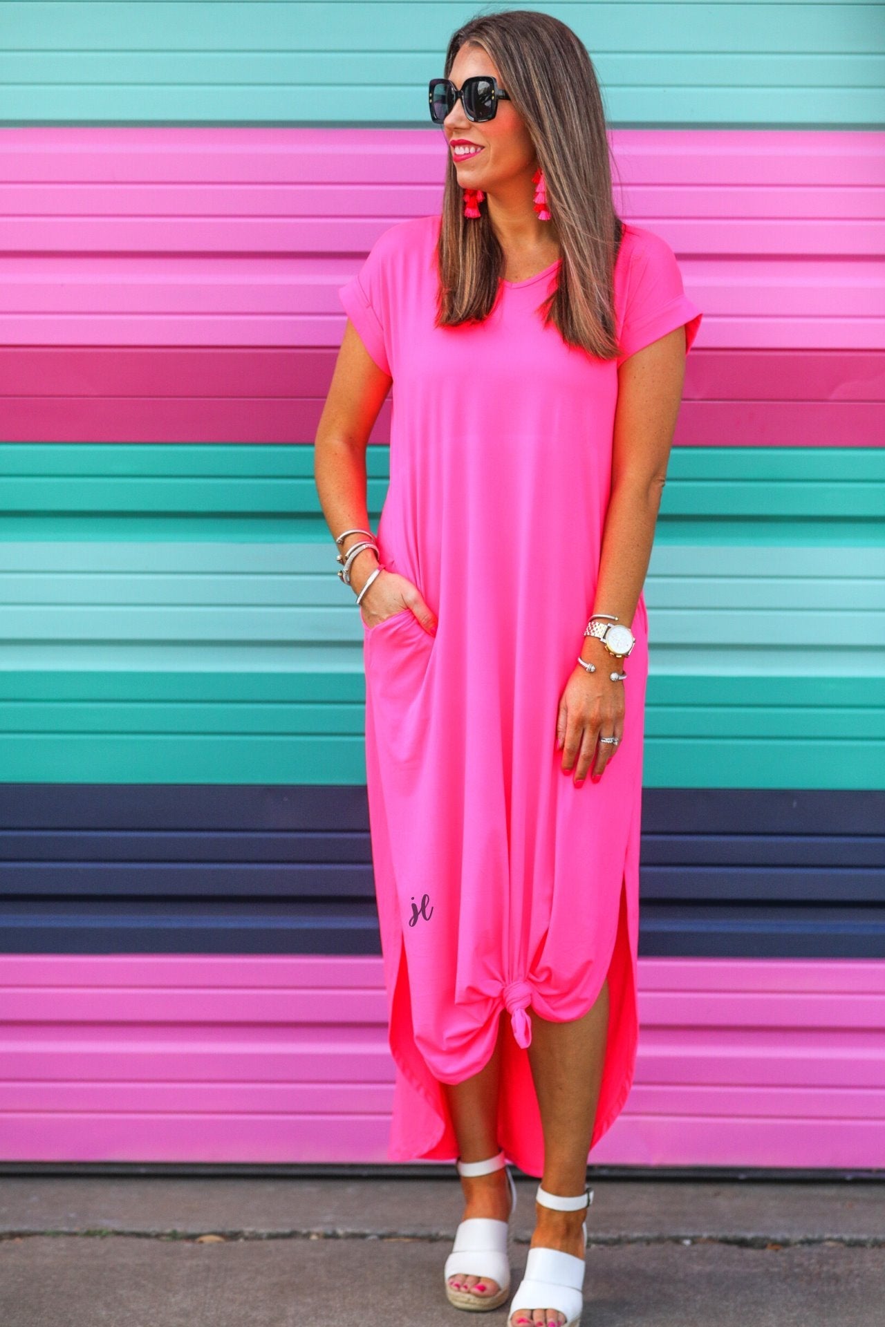 oversized short-sleeve t-shirt dress crafted from soft, stretchy material with a V-neckline, cuffed sleeves, side slits, and pockets on a solid hot pink fabric