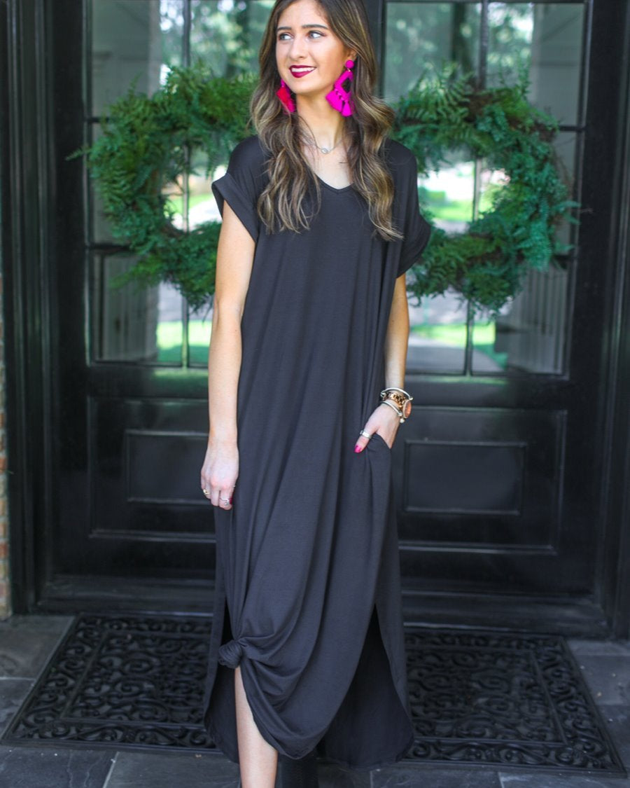 oversized short-sleeve t-shirt dress crafted from soft, stretchy material with a V-neckline, cuffed sleeves, side slits, and pockets on a solid black fabric