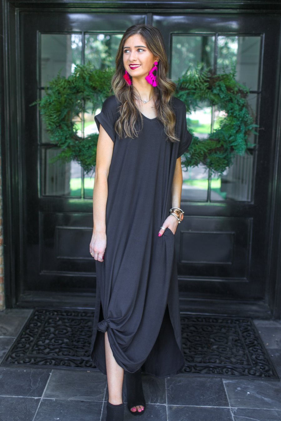 oversized short-sleeve t-shirt dress crafted from soft, stretchy material with a V-neckline, cuffed sleeves, side slits, and pockets on a solid black fabric