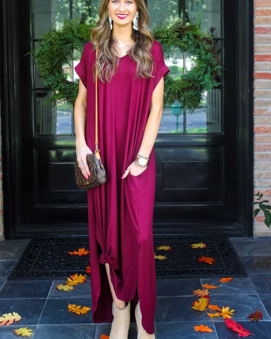 oversized short-sleeve t-shirt dress crafted from soft, stretchy material with a V-neckline, cuffed sleeves, side slits, and pockets on a solid burgundy fabric