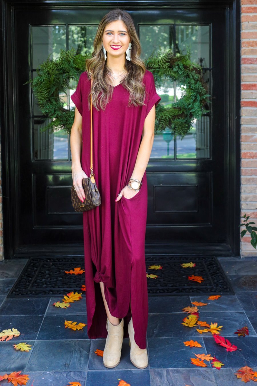 oversized short-sleeve t-shirt dress crafted from soft, stretchy material with a V-neckline, cuffed sleeves, side slits, and pockets on a solid burgundy fabric