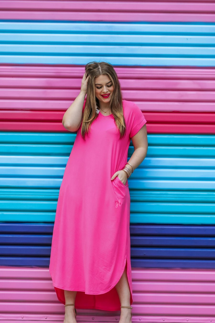oversized short-sleeve t-shirt dress crafted from soft, stretchy material with a V-neckline, cuffed sleeves, side slits, and pockets on a solid fuchsia fabric