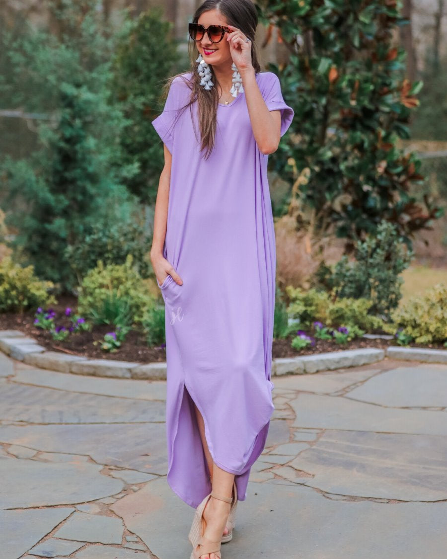 oversized short-sleeve t-shirt dress crafted from soft, stretchy material with a V-neckline, cuffed sleeves, side slits, and pockets on a solid lavender fabric