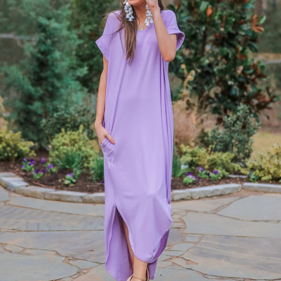 oversized short-sleeve t-shirt dress crafted from soft, stretchy material with a V-neckline, cuffed sleeves, side slits, and pockets on a solid lavender fabric