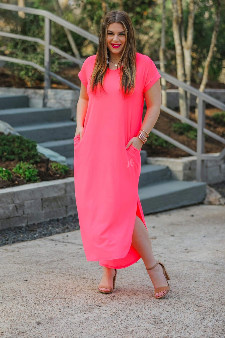 oversized short-sleeve t-shirt dress crafted from soft, stretchy material with a V-neckline, cuffed sleeves, side slits, and pockets on a solid neon coral fabric