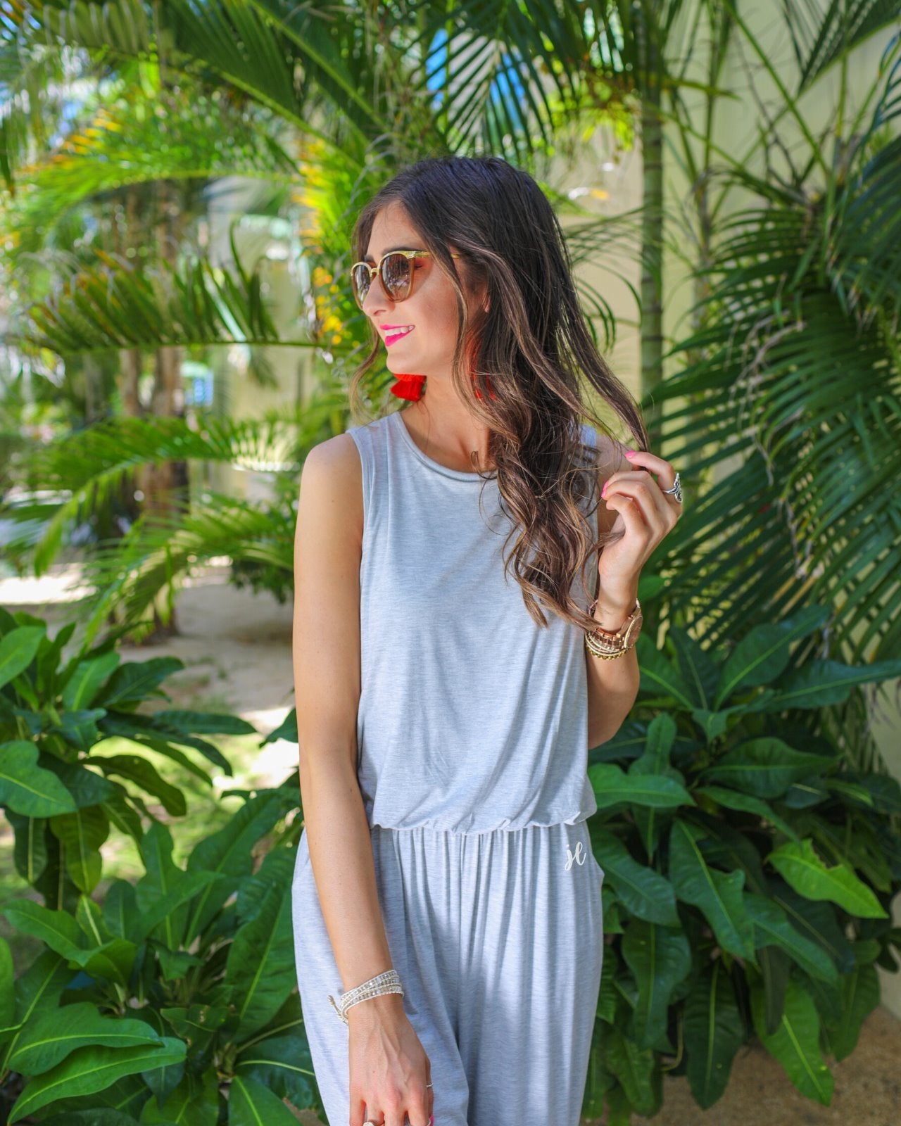 a grey sleeveless one-piece jumpsuit with wide 2.5" shoulder straps, a rounded neckline, elastic waist, side pockets, keyhole button back, and a relaxed flare leg silhouette