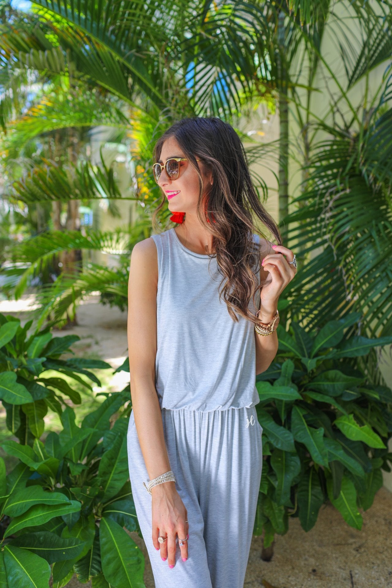 a grey sleeveless one-piece jumpsuit with wide 2.5" shoulder straps, a rounded neckline, elastic waist, side pockets, keyhole button back, and a relaxed flare leg silhouette