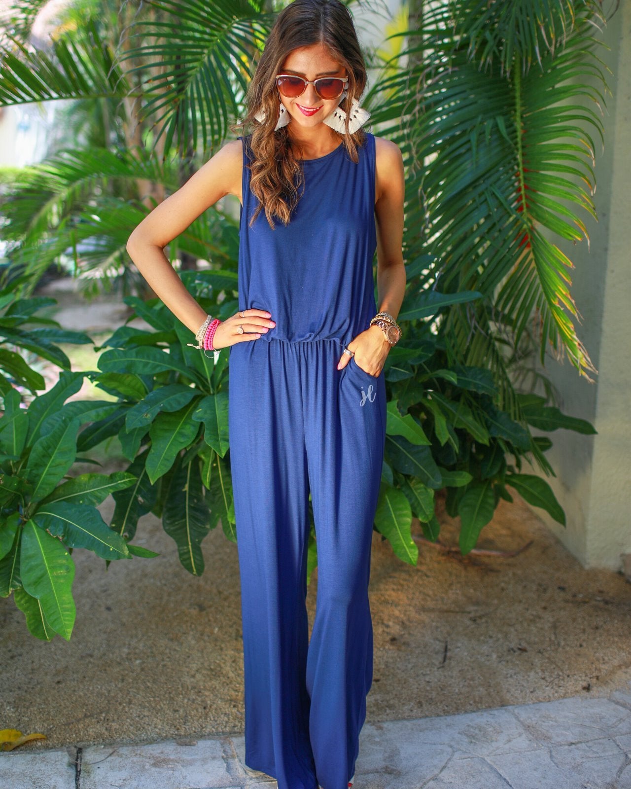 a navy sleeveless one-piece jumpsuit with wide 2.5" shoulder straps, a rounded neckline, elastic waist, side pockets, keyhole button back, and a relaxed flare leg silhouette