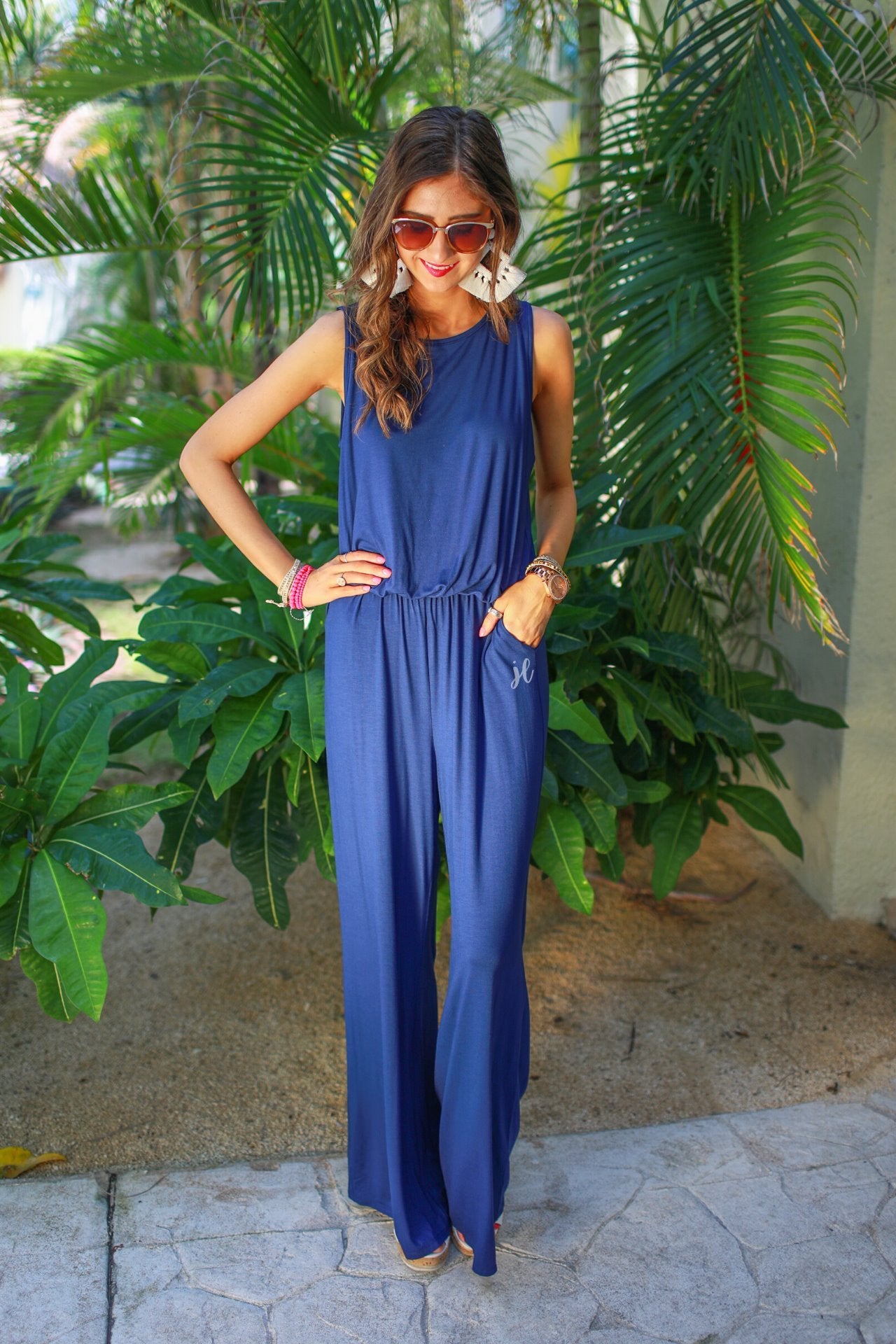 a navy sleeveless one-piece jumpsuit with wide 2.5" shoulder straps, a rounded neckline, elastic waist, side pockets, keyhole button back, and a relaxed flare leg silhouette