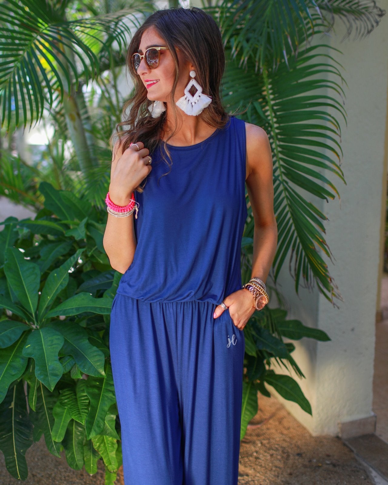 a navy sleeveless one-piece jumpsuit with wide 2.5" shoulder straps, a rounded neckline, elastic waist, side pockets, keyhole button back, and a relaxed flare leg silhouette