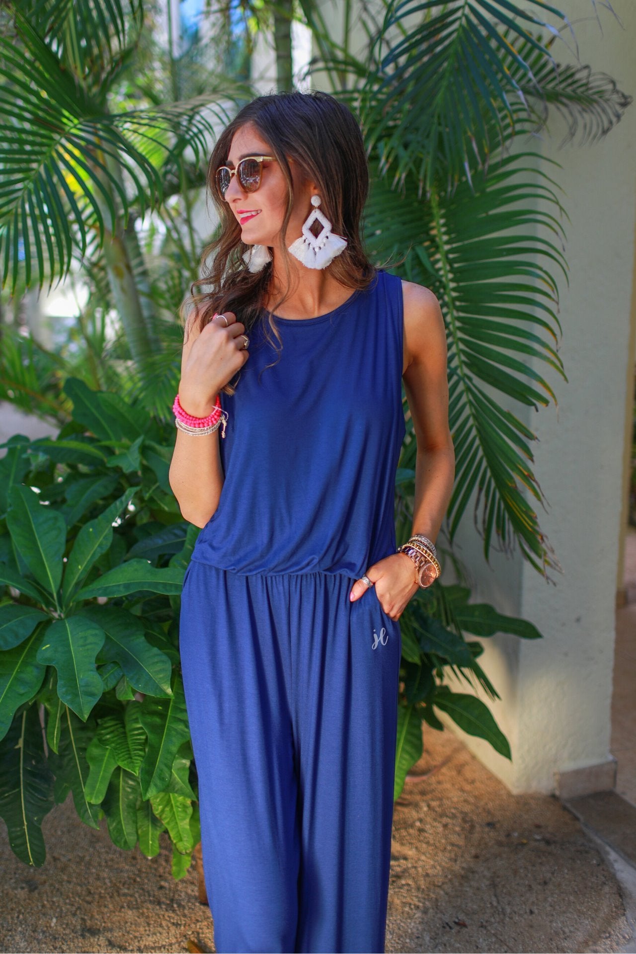 a navy sleeveless one-piece jumpsuit with wide 2.5" shoulder straps, a rounded neckline, elastic waist, side pockets, keyhole button back, and a relaxed flare leg silhouette