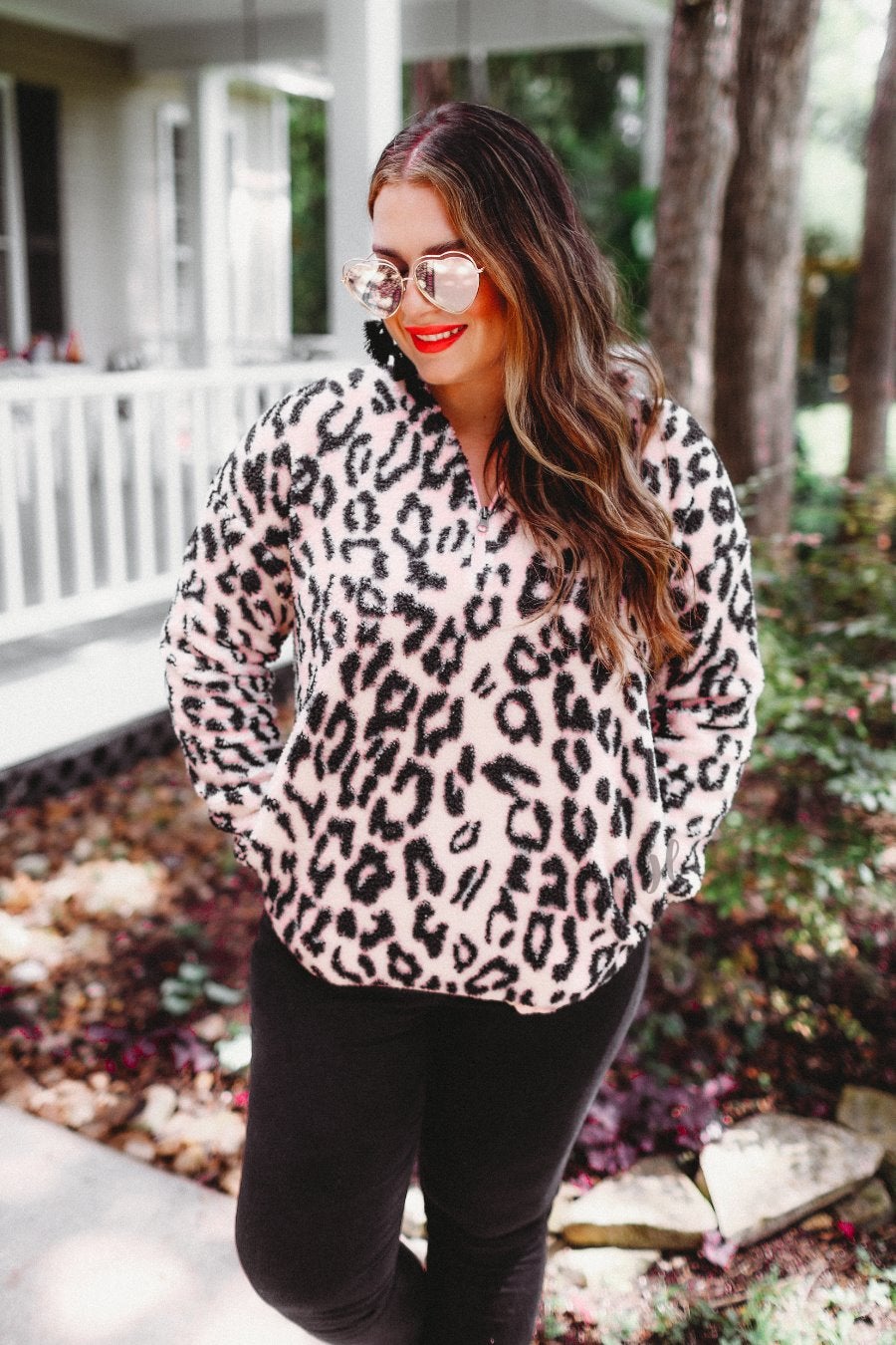 a long-sleeve fluffy pullover with a quarter zip, convenient front pockets, a foldable collar, and an elastic band at the hemline on a pink leopard sherpa fabric
