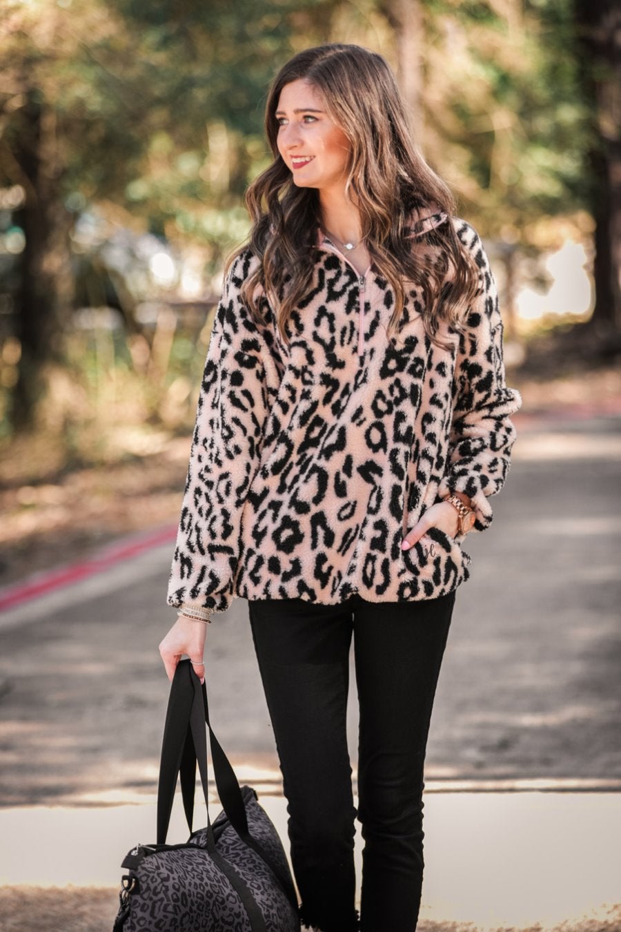 a long-sleeve fluffy pullover with a quarter zip, convenient front pockets, a foldable collar, and an elastic band at the hemline on a pink leopard sherpa fabric