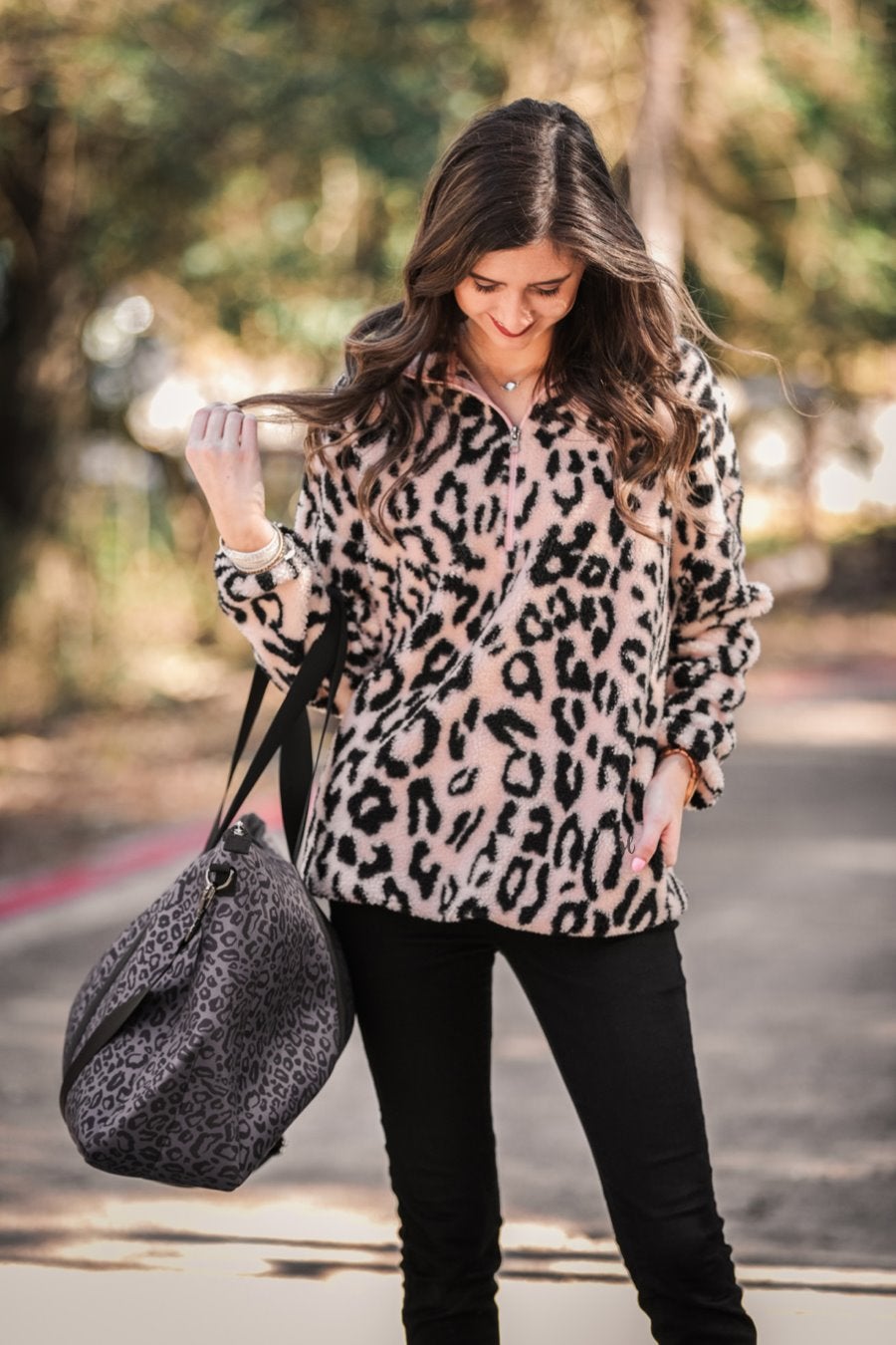 a long-sleeve fluffy pullover with a quarter zip, convenient front pockets, a foldable collar, and an elastic band at the hemline on a pink leopard sherpa fabric