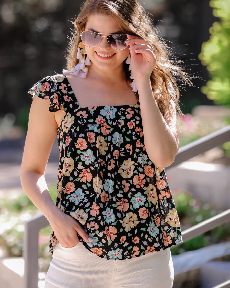 a sleeveless tank with a squared neckline, ruffle tank sleeves, and a flowy body on a floral pattern and black base