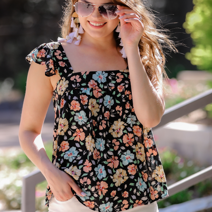 a sleeveless tank with a squared neckline, ruffle tank sleeves, and a flowy body on a floral pattern and black base