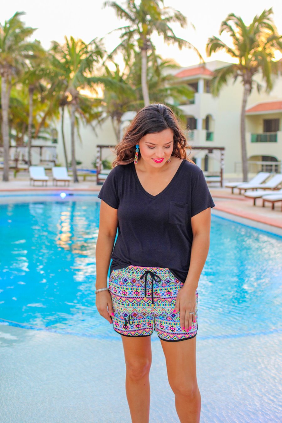 mid-rise relaxed fit activewear shorts with side pockets and a tie waist drawstring with gold bead accents, designed on an Aztec pattern print fabric, ivory base, and black trim