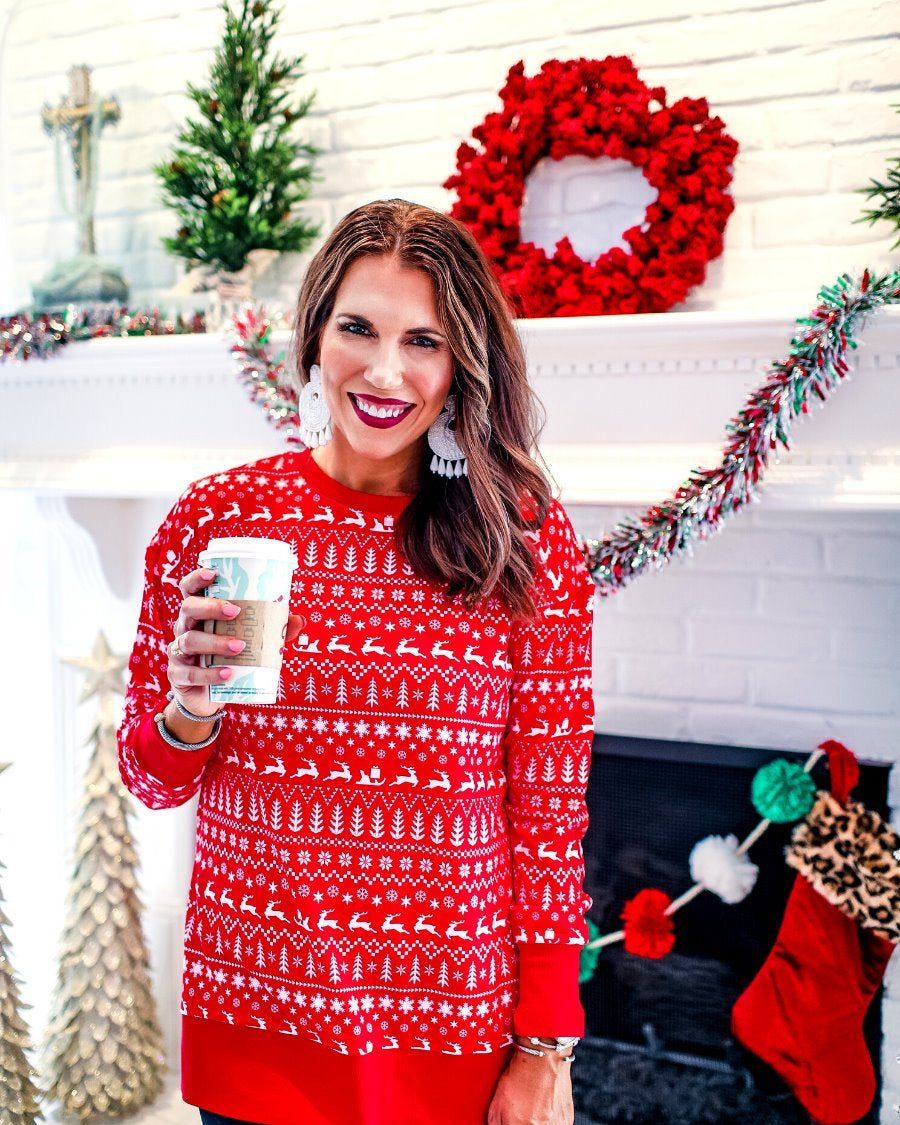 a red long-sleeve tunic made from comfy material with comfy material with a sublimation-printed Christmas pattern print (geometric designs, reindeer, Santa's sleigh, snowflakes, and trees) sublimation detail, ribbed accents (cuffs, neckline, and hem), side slits, and a relaxed fit