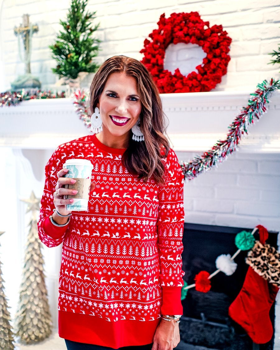 a red long-sleeve tunic made from comfy material with comfy material with a sublimation-printed Christmas pattern print (geometric designs, reindeer, Santa's sleigh, snowflakes, and trees) sublimation detail, ribbed accents (cuffs, neckline, and hem), side slits, and a relaxed fit