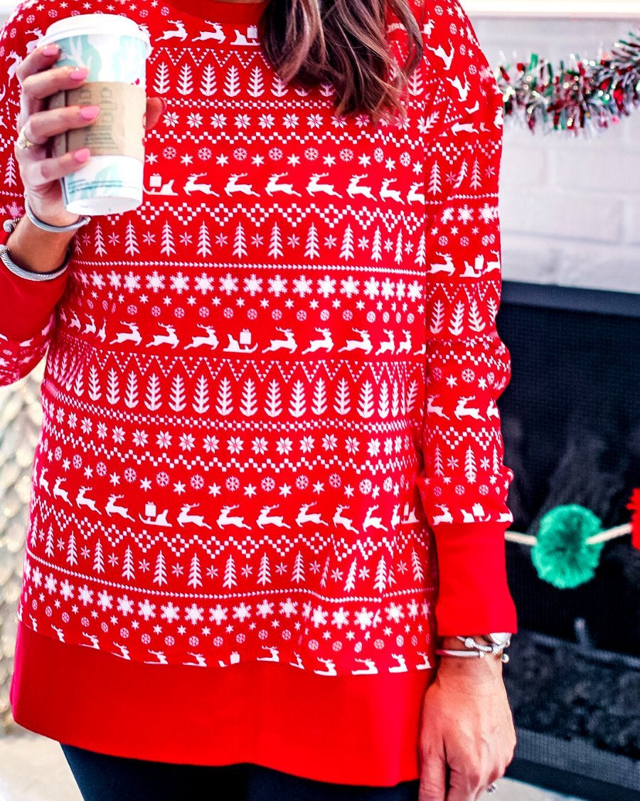 a red long-sleeve tunic made from comfy material with comfy material with a sublimation-printed Christmas pattern print (geometric designs, reindeer, Santa's sleigh, snowflakes, and trees) sublimation detail, ribbed accents (cuffs, neckline, and hem), side slits, and a relaxed fit