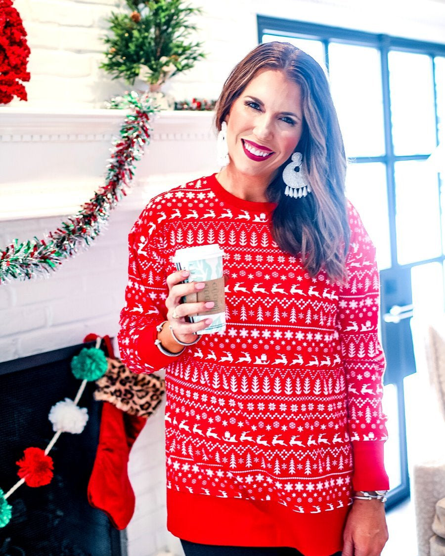 a red long-sleeve tunic made from comfy material with comfy material with a sublimation-printed Christmas pattern print (geometric designs, reindeer, Santa's sleigh, snowflakes, and trees) sublimation detail, ribbed accents (cuffs, neckline, and hem), side slits, and a relaxed fit