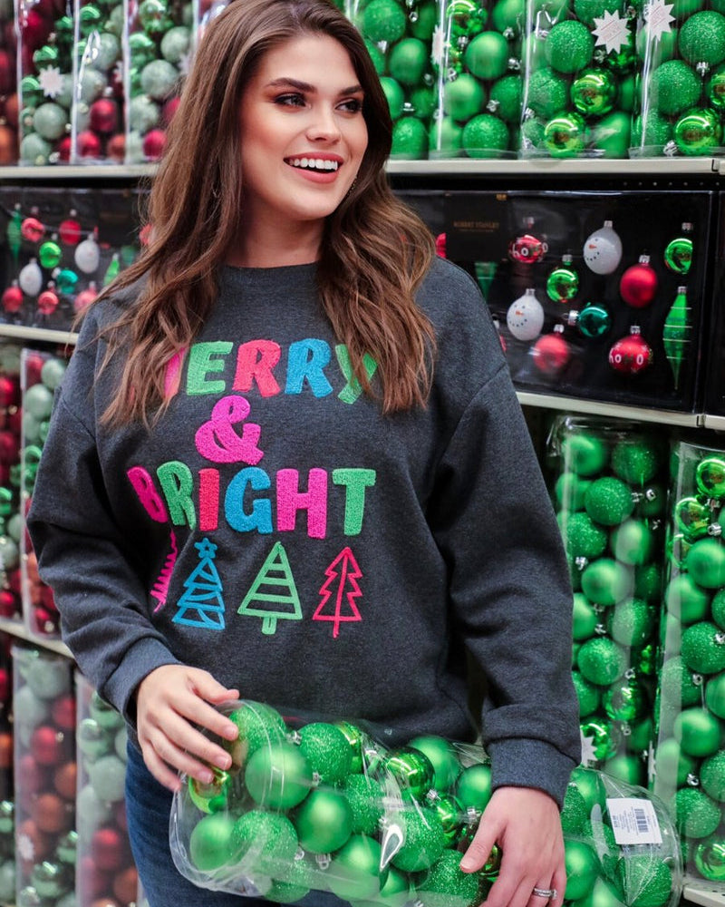 a charcoal long-sleeve sweatshirt with a fuzzy inside, sewn on color chenille letters, and Christmas tree patches