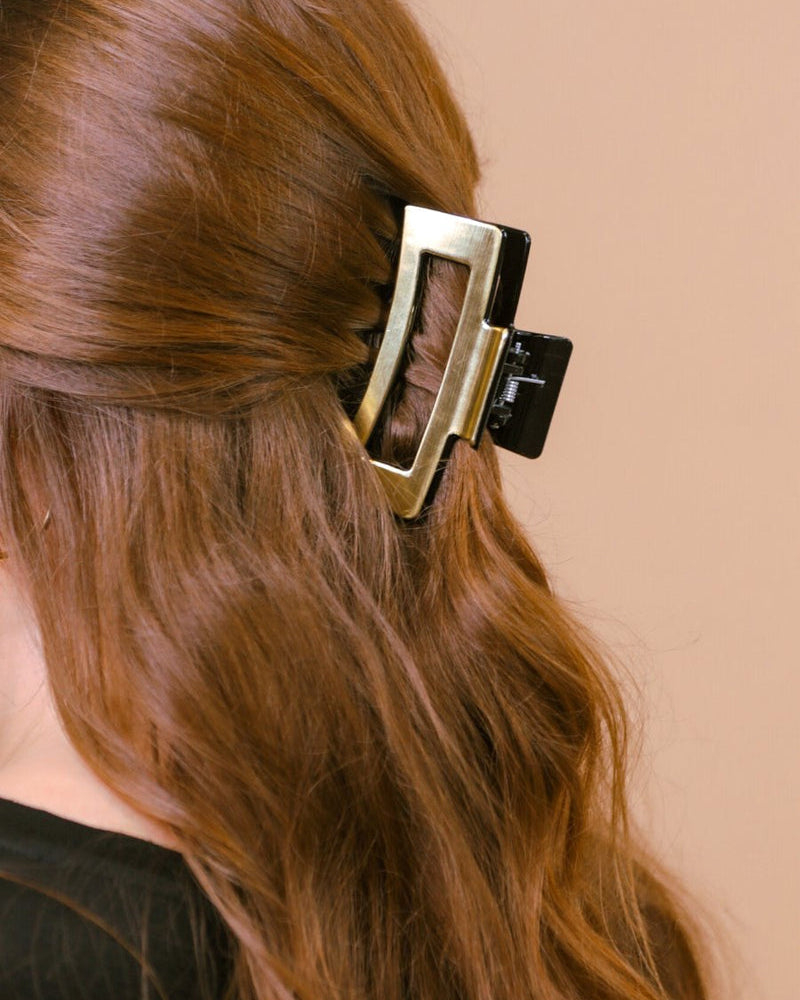 a metallic claw clip with a strong hold and sleek shine in gold