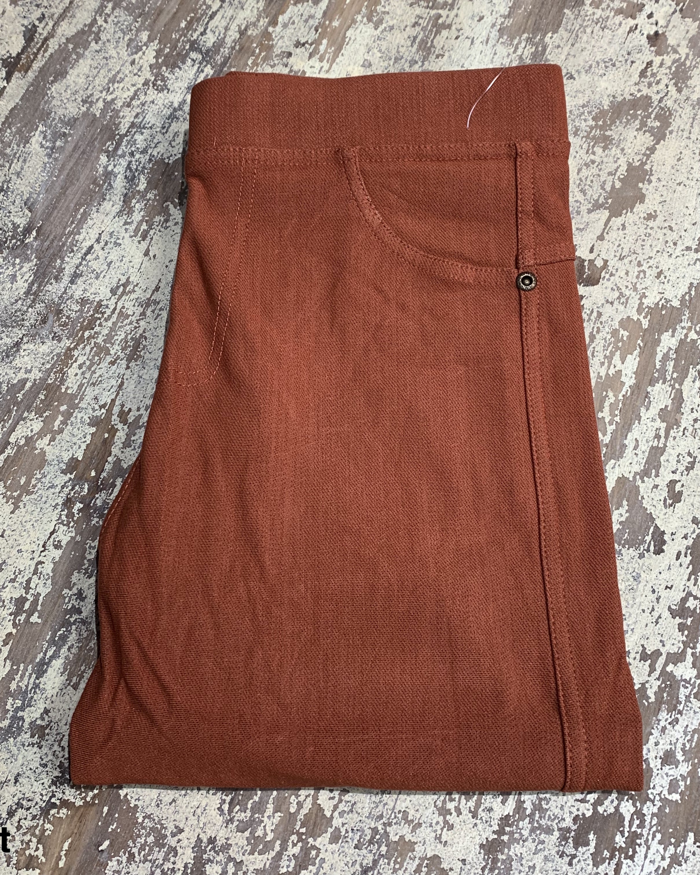 solid pull-on style leggings made of premium stretch fabric thicker than regular leggings, an elastic waistband, double back pockets, and a unique stripe detailing on the inside in rust