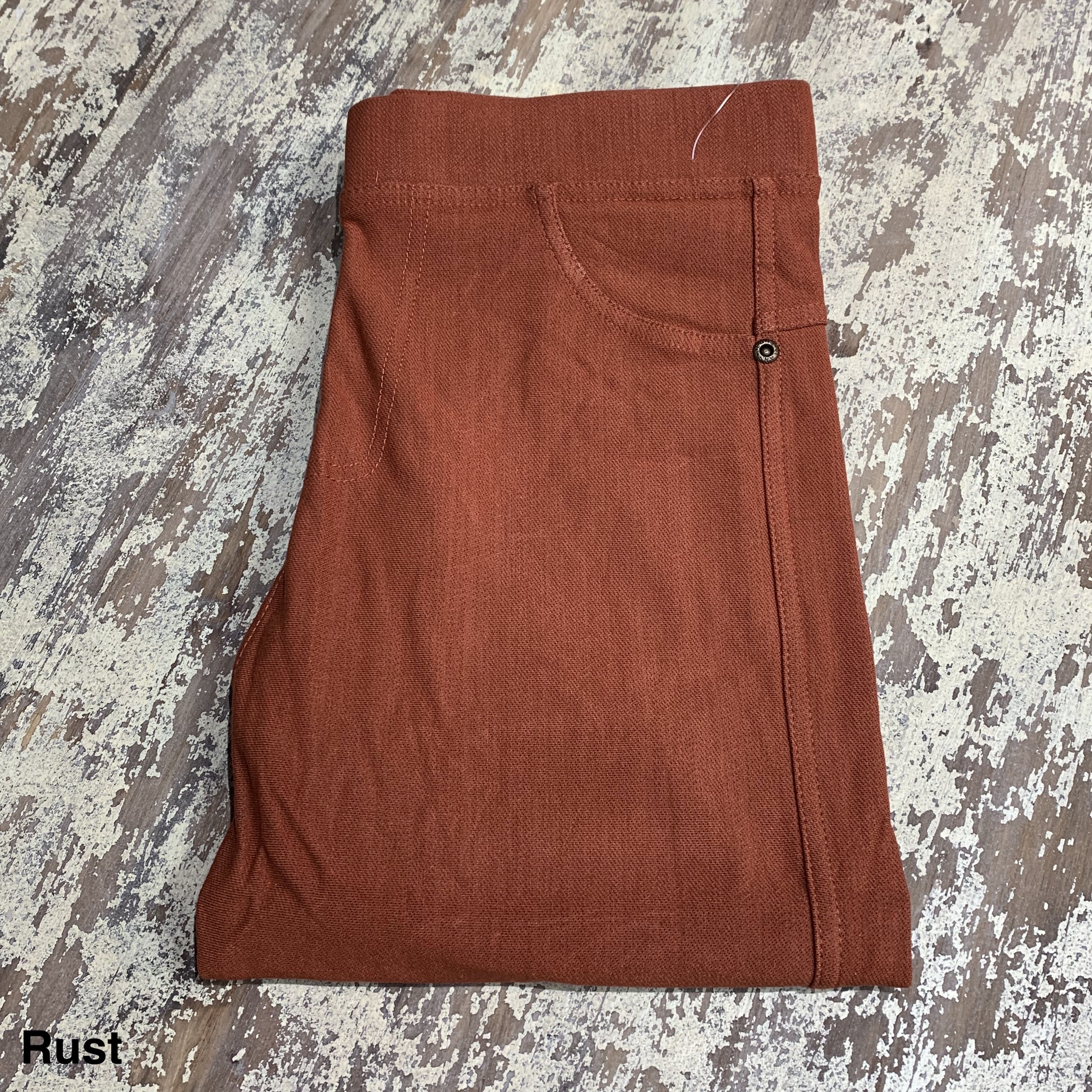 solid pull-on style leggings made of premium stretch fabric thicker than regular leggings, an elastic waistband, double back pockets, and a unique stripe detailing on the inside in rust