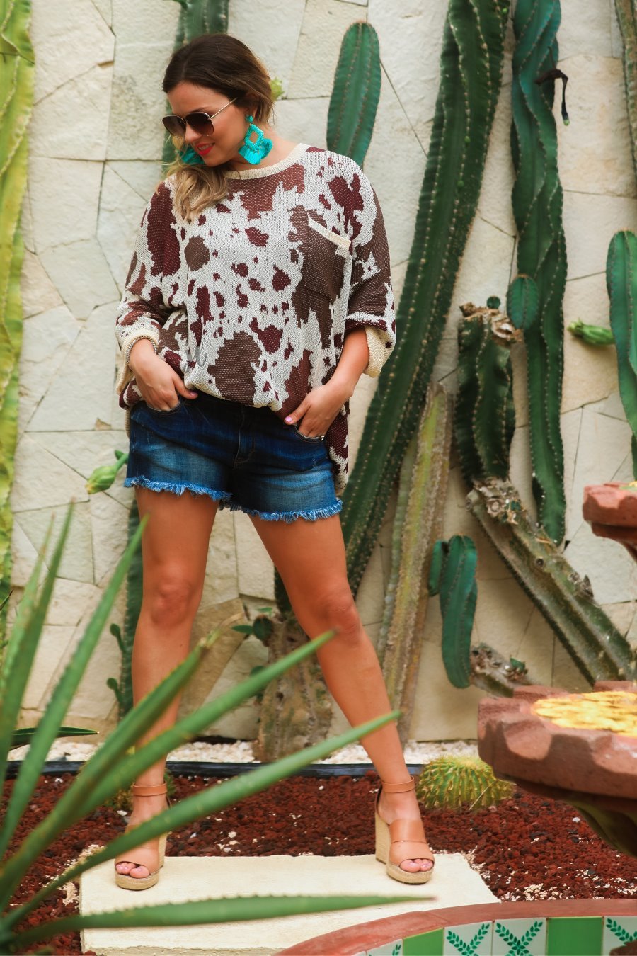 three-quarter cuffed sleeve unlined sweater crafted from a loose knit material with an oversized fit, a rounded neckline, a chest pocket, and trim on the collar, hem, and pocket on a brown cow print and cream base