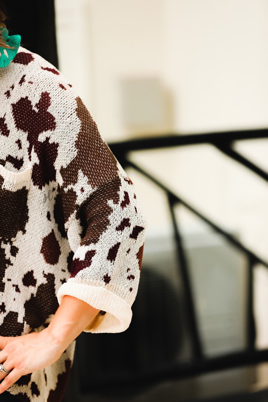 three-quarter cuffed sleeve unlined sweater crafted from a loose knit material with an oversized fit, a rounded neckline, a chest pocket, and trim on the collar, hem, and pocket on a brown cow print and cream base