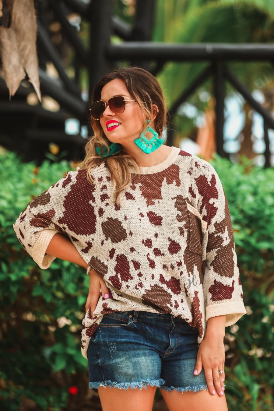 three-quarter cuffed sleeve unlined sweater crafted from a loose knit material with an oversized fit, a rounded neckline, a chest pocket, and trim on the collar, hem, and pocket on a brown cow print and cream base