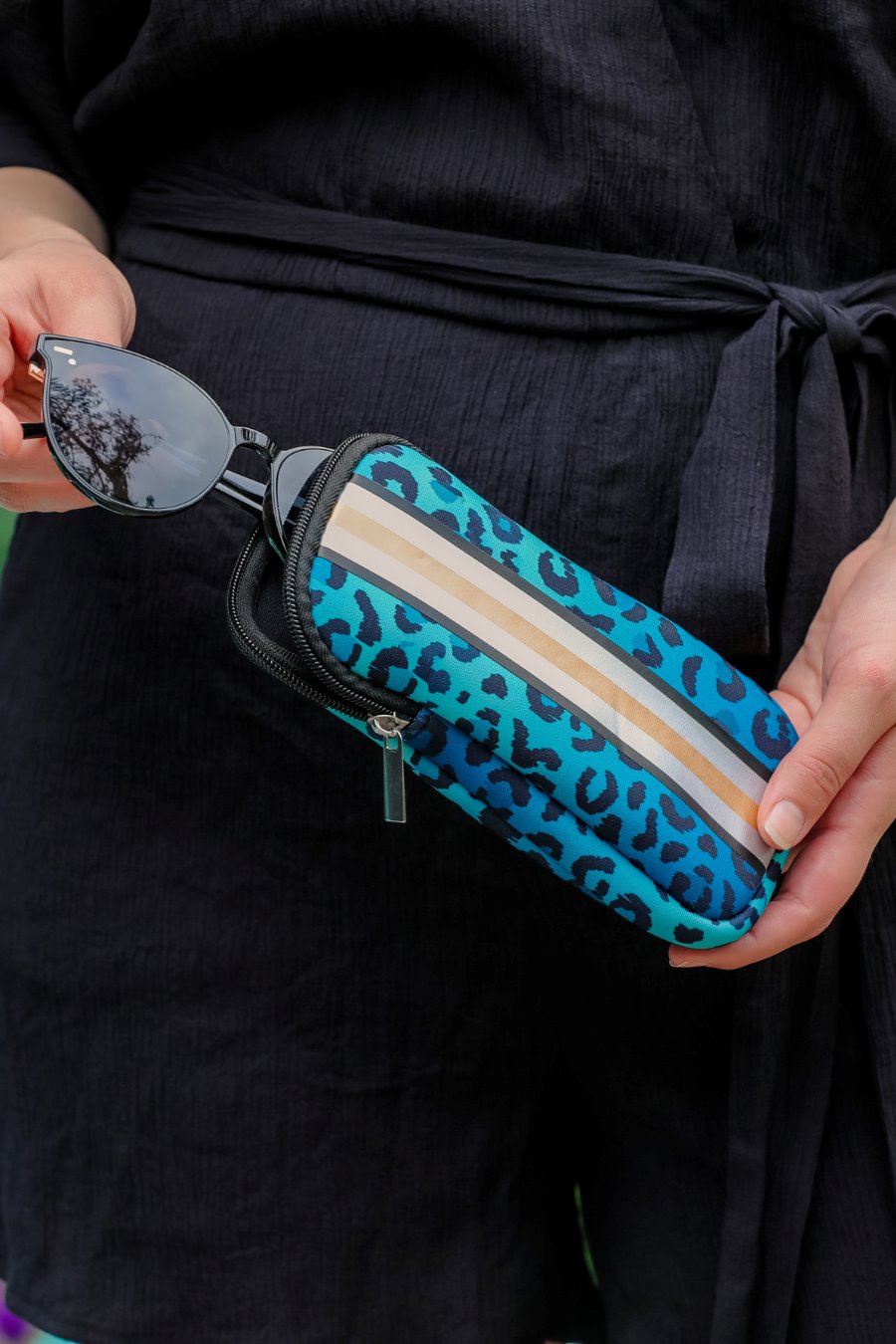 ultra-lightweight sunglasses case made of neoprene with a top double zipper in silver hardware and corresponding racing stripes in turquoise leopard