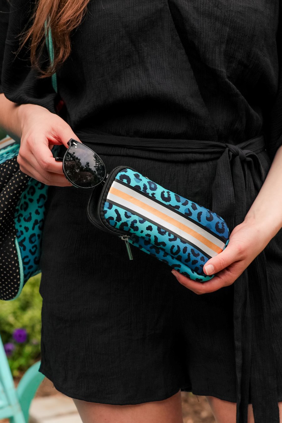 ultra-lightweight sunglasses case made of neoprene with a top double zipper in silver hardware and corresponding racing stripes in turquoise leopard